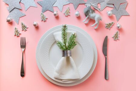Christmas white winter table setting with reindeer on pastel pink background. Top view. Xmas dinner.の写真素材