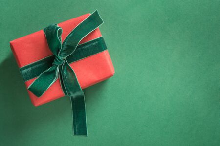 Christmas red giftwit green velvet ribbon on green background. Greeting card. Happy New Year. Space...