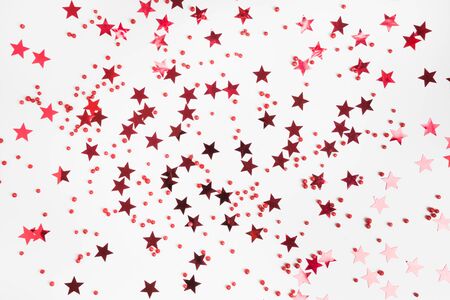 Party holiday backdrop with red stars glitter confetti on white background. View from above, flat...