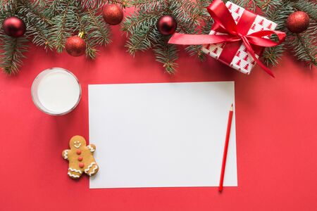 Christmas checklist or empty blank letter for Santa Claus with glass of milk, cookies, gingerbread on red. Space for your text. Flat lay. View from above. Invitation.の写真素材