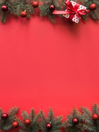 Christmas frame with fir branches, red balls, garland on red background. Space for text, view from above, flat lay.の写真素材
