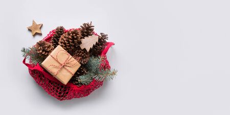 Christmas zero waste decor in red cotton eco bag on grey. Cones and fir tree branches for handmade design.の写真素材
