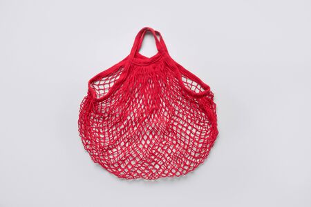 Empty eco shopping red mesh bag on grey. Zero wasteconcept. Space for text. View from above. Eco friendly.の写真素材
