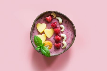 Healthy breakfast banana and blueberry smoothie decorated with fruits in coconut bowl on pink background. View from above. Clean eating, vegetarian food concept.の写真素材