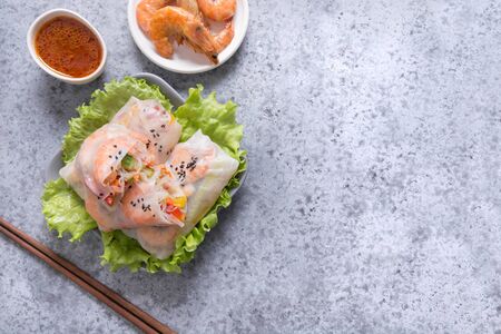 Spring rolls with prawn, noodles and vegetables in rice paper on grey stone background. Close up....