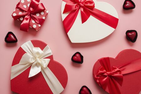 Valentines day greeting card. Pattern of red gift boxes heart shaped and chocolate sweets on pink....