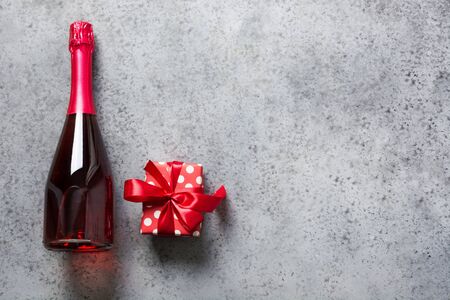 Valentines day card. Bottle of rose sparkling wine and gift box on grey. Top view. Space for text.の写真素材