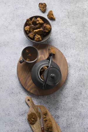 Organic Chaga tea in cup. Trendy Russian healthy infusion from birch mushroom on light background....