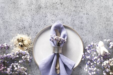 Easter table setting with grey plate and violet decor on grey stone table. Elegance dinner. Top view. Space for text.の写真素材