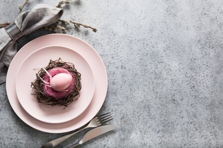 Easter table setting with pink plate and golden eggs on grey stone table. Elegance dinner. Top view....
