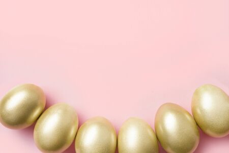 Golden eggs as border on pastel pink. Happy Easter background. Top view with copy space.の写真素材