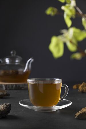 Organic Chaga mushrooms hot beverage in glass cup on black. Trendy healthy clean eating drink on dark background.の写真素材