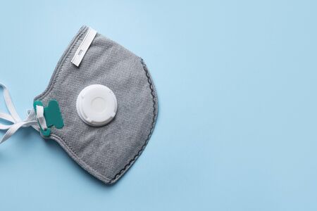 Reusable antiviral mask with breather filter valve and activated carbon filter on blue. Prevention...