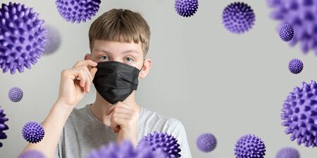 Teenager puts on protective black mask against coronavirus and bacteria. Space for text. Prevention of Covid 19. Quarantine.の写真素材