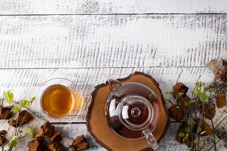 Chaga mushrooms infusion in glass teapot on white wooden board. Top view. Copy space.の写真素材