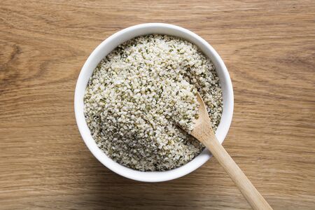 Organic kernels hemp in white bowl on wooden board. View from above. Close up.の写真素材