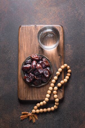 Ramadan. Wooden prayer beads and dates in bowl on brown. View from above. Vertical format. Eid Mubarak. Religious tradition.の写真素材