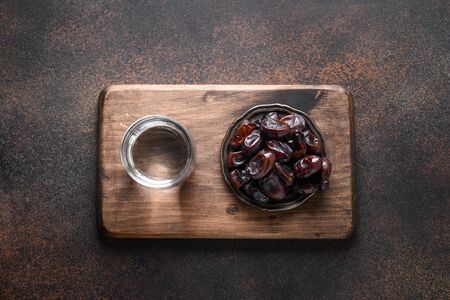 Ramadan. Dates in bowl and water on brown background. View from above. Eid Mubarak. Religious tradition.の写真素材