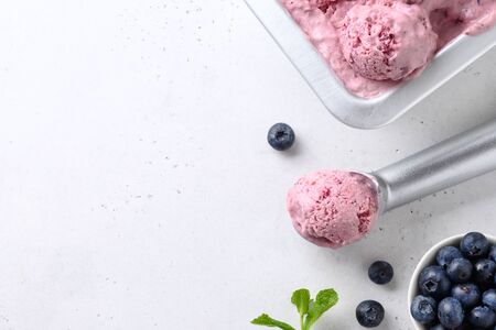 Bluberry and banana homemade ice cream or sorbet ball in scoop on white background. Close up. Space...