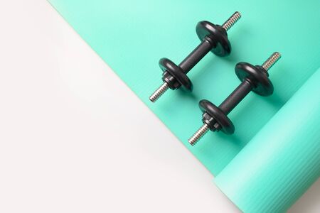 Sport black dumbbells on turquoise yoga mat on grey background. Copy space. Flat lay. View from above.の写真素材