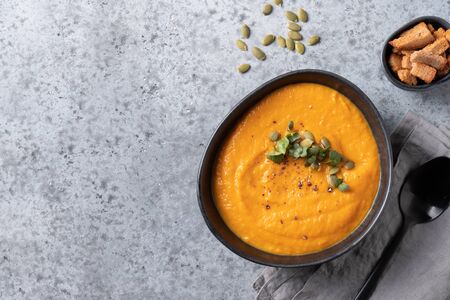 Fall pumpkin soup with cream garnish microgreens on grey background. View from above. Copy space.の写真素材
