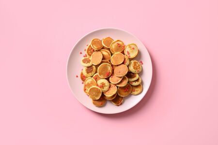 Tiny cereals pancake with blueberry on pink background. View from above. Tasty breakfast.