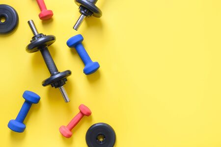 Sport colorful dumbbells on yellow background. View from above, copy space.の写真素材