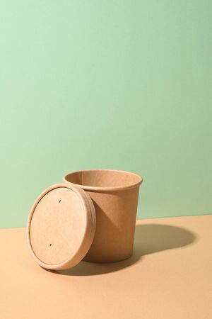Craft paper soup cup with shadow on green and brown paper background. Empty container for take away food. Ecological individual package. Zero Waste.の写真素材