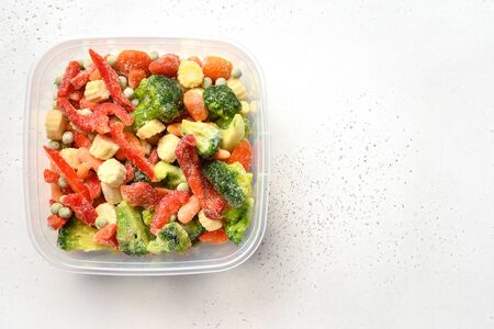 Frozen colorful vegetables in container on white background. View from above.の写真素材