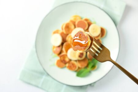 Pouring honey on homemade tiny cereal pancakes on white background. Close up.の写真素材