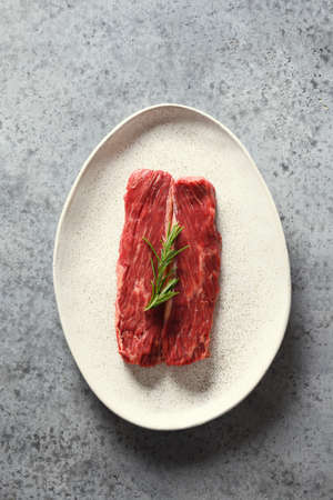 Raw marbled ribeye steak with rosemary on grey. Top view. Vertical format.の写真素材
