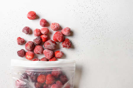 Frozen strawberries in plastic packet on white background. View from above. Stocks. Copy space. Healthy eating. Vitamins. Vegetarian, vegan food.の写真素材