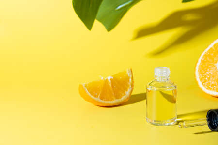 Cosmetic hyaluronic acid or hydrating oil and orange essence on yellow background. Anti-cellulit care. Space for text.の写真素材
