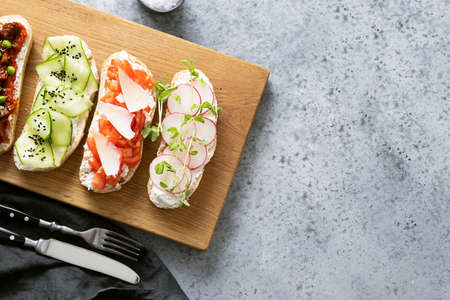 Sandwiches with vegetables, radishes, tomatoes, cucumbers and microgreens on gray. View from above. Space for text.の写真素材