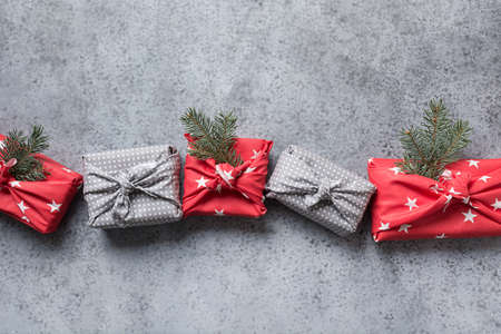 Christmas gifts wrapped in red textile with decor. Sustainable gifts. Zero waste. Xmas eco holiday. Traditional Japanese Furoshiki style. View from above. Flat lay. Banner.の写真素材