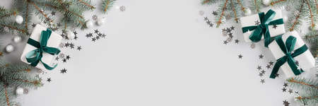Christmas banner with gifts, xmas fir branches and white decor on grey. Merry christmas card. Winter holiday. Happy New Year. Space for textの写真素材
