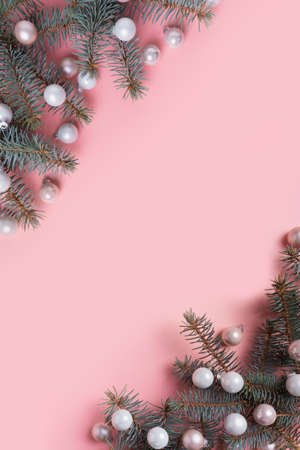 Christmas white balls and fir branches on pink. Xmas vertical banner with space for text. View from above. Flat lay style.の写真素材