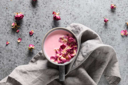 Rose moon milk in grey cup and rose petals on grey background. Top view. Close up.の写真素材