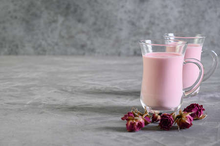 Rose moon milk and dry roses on grey background. Copy space.