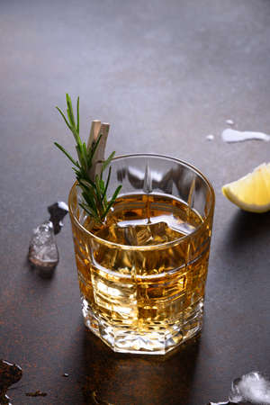 One shot of whiskey with rosemary on dark brown. Vertical orientation.の写真素材