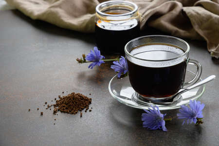 Chicory beverage in glass cup, concentrate and flowers. Healthy herbal beverage, coffee substitute. Front view. Close up. Copy space.の写真素材