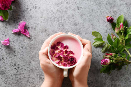 Rose moon milk in child hands on grey. Top view. Ayurveda warm drink. Nice in case of sleeplessness.の写真素材