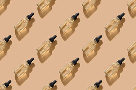 Beauty seamless pattern of cosmetic oil in glass bottle on beige. Top view.の写真素材