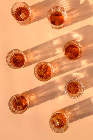 Many glasses of cold whiskey served in rocks for pasty on beige trendy background. View from above.
