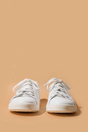 White female gumshoes or sneakers on beige background. Vertical format. Copy space.の写真素材