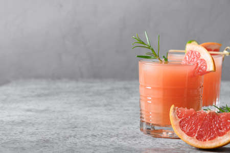 Two grapefruit sparkling cocktails or lemonade garnish rosemary sprigs on light grey background. Space for text.の写真素材