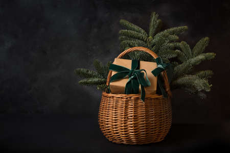 Christmas holiday gift hamper with craft gift and evergreen spice branches on black background. Xmas greeting card with copy space.の写真素材
