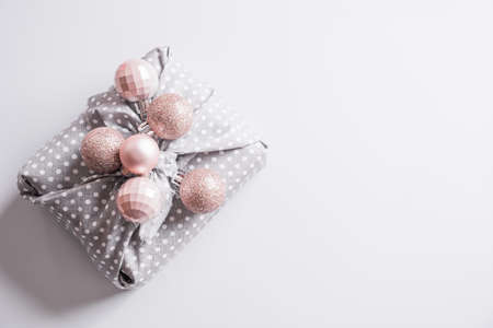 Christmas sustainable gift decorated pastel silver pink balls on gray background with copy space. Xmas greeting card. Happy New Year.の写真素材