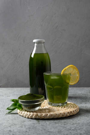 Chlorella healthy Detox beverage with lemon in glass on a gray background. Close up. Vertical format.の写真素材