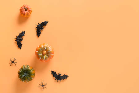 Halloween fun party decorations, pumpkins, bat, spooky spiders on orange background. Overhead view,...
